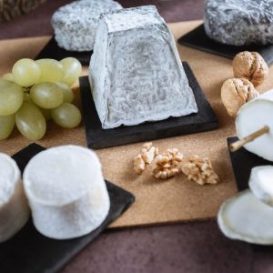 Plateau avec une sélection des fromages de chèvre Verneuil (pyramide, bûche, ronds), accompagnés de grains de raisin et de cerneaux de noix.